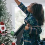 girl and dad in pajamas decorating a christmas tree