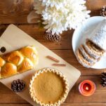 pumkin pie and challah bread on a bread board with a pumpkin roll on a white plate