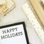 white rug with gift wrap roles laying on top and a plaque that says Happy Holidays