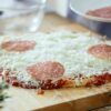 homemade pepperoni pizza being assembled with fresh dough, mozzarella cheese, and large pepperoni